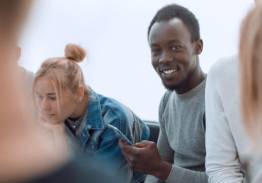 smiling guy sitting in a circle of her friends