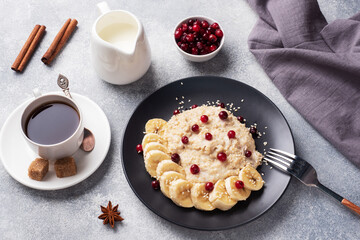 Oatmeal with milk with banana cranberries and sesame seeds. A Cup of coffee, healthy Breakfast Concept.