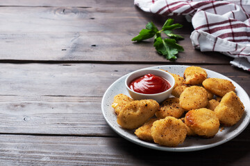 Fried chicken nuggets with tomato ketchup sauce. Wooden background. Copy space.