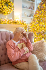 Senior woman sitting on a sofa with a photo in her hand and looking lonely