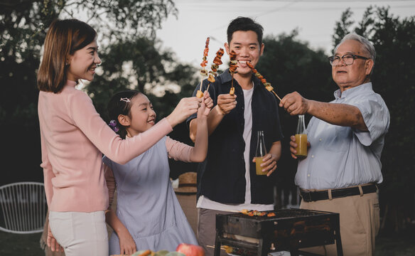 Asian Family Having A Barbecue Party At Home. Cooking Grilled Bbq For Dinner In Backyard. Lifestyle On Summer Holiday.