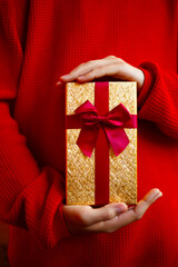 beautiful bright gift in the hands of a child on a red background