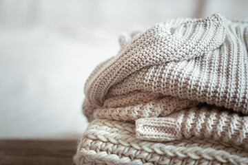 Fototapeta na wymiar A stack of warm knitted items on blurred white background copy space.