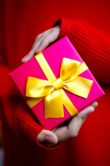 beautiful bright gift in the hands of a child on a red background
