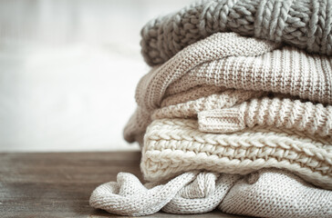 Fototapeta na wymiar A stack of warm knitted items on blurred white background copy space.