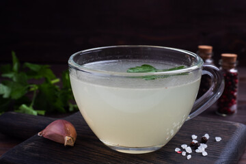 Chicken broth in a glass Cup. Boiled chicken leg quarters. Healthy food with collagen and amino acids.