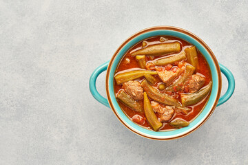 Homemade okra and meat stew in a pot. Top view, copy space