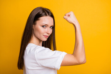 Photo portrait of strong girl flexing biceps isolated on bright yellow colored background