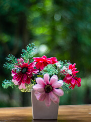 Fake red and pink flower on the table with blur background