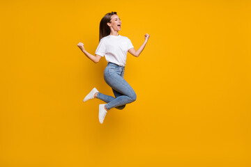 Full length body size photo of cheerful overjoyed girl fan jumping gesturing like winner yelling isolated bright yellow color background