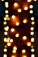 Golden and white Christmas lights against black background. Defocused