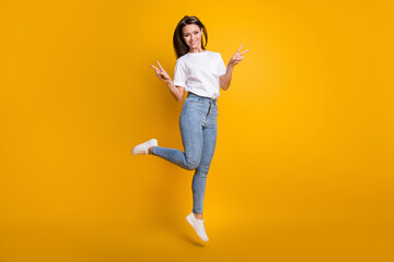 Fototapeta na wymiar Full length body size photo of girl demonstrating v-signs peace with both hands isolated on bright yellow color background