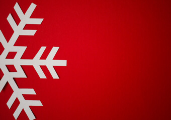 One white cut out paper snowflake on Christmas red background, greeting card