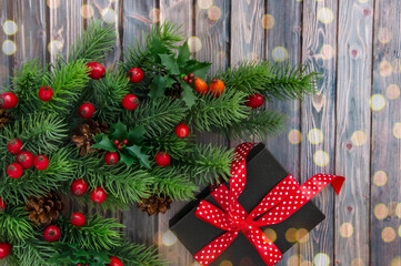 Decorated branches of a Christmas tree, cones, red berries and gifts on a wooden table. Christmas...