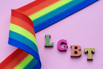 Gay pride letters LGBT with rainbow ribbon on pink ground