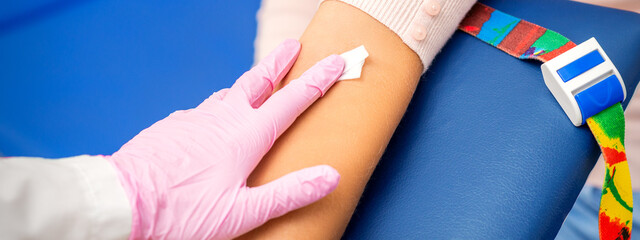 Hand of nurse applying cotton swab to arm of young woman after blood sample in the hospital © okskukuruza