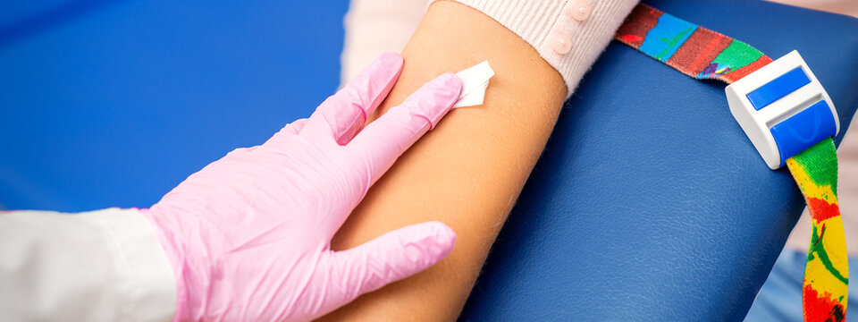 Hand Of Nurse Applying Cotton Swab To Arm Of Young Woman After Blood Sample In The Hospital