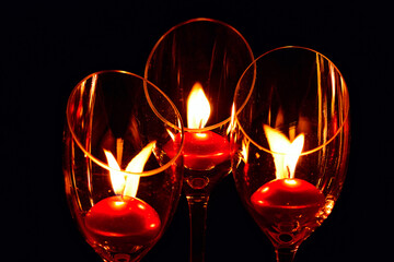 Three red candle lights in clear goblets on black background. Concept of Holiday Season and memory