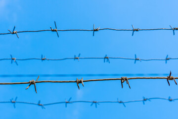 Barbed wire horizontally against the blue sky.