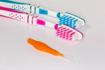Interdental brush against the usual toothbrushes, closeup in selective focus
