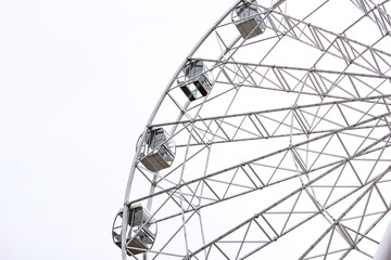 Modern white Ferris wheel in the central park against sky. Entertainment, attraction, amusement park, minimal concept or background.
