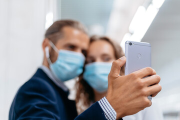 young couple in protective masks taking selfies in subway.