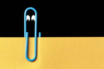 Paperclip with eyes and a sheet of paper