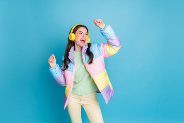 Photo portrait of excited girl dancing wearing yellow headset isolated on pastel blue colored background