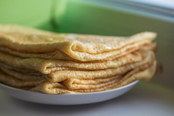 A stack of homemade pancakes on the windowsill. Traditional Russian pastries.