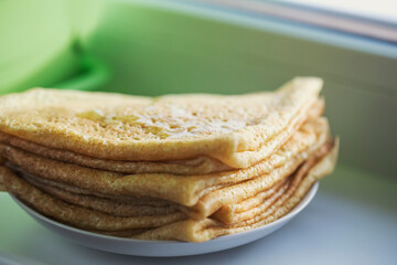A stack of homemade pancakes on the windowsill. Traditional Russian pastries.