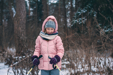 Fototapeta na wymiar happy child girl skiing in winter snowy forest, spending holidays outdoor. Active winter sports.