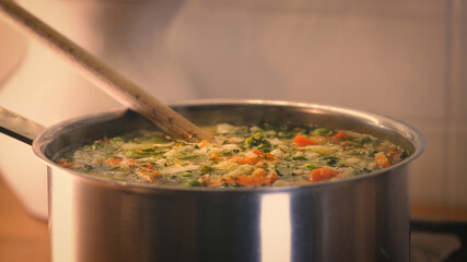 stirring a pot of vegetable soup. Minestrone soup boiling in the pot. Vegetarian healthy meal for dinner. meal for lunch, hot and cozy soup for dinner at home