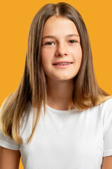Happy kid portrait. Positive attitude. Peaceful childhood. Cheerful friendly calm girl in white t-shirt smiling looking at camera isolated on orange background.