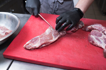 Cutting pork meat. Chef working in the kitchen in a pub