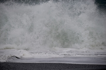 close detail of a large wave that hits the beach in a stormy day
