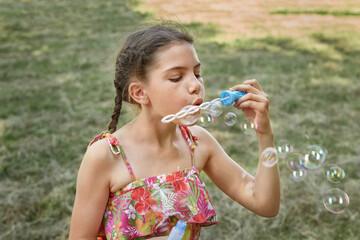 A little girl on summer vacation blows soap bubbles. Sunny summer warm day.