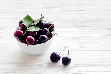 Plate of ripe red cherries with leaves, close up