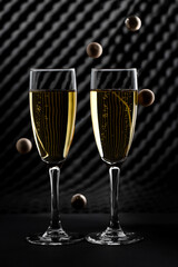 Composition of two glasses with champagne and balls as bubbles. Checkered background.
