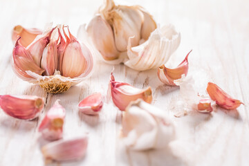 Garlic bulb and garlic cloves on white wooden background