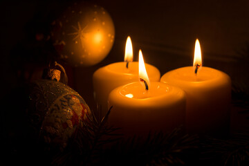 White candles with Christmas tree branches and Christmas tree toys on a dark background. The candle...