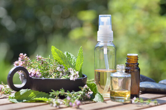  Bottle Of Essential Oils Spilled On A  Table With  Lavender Flowers On Green Bokeh Background