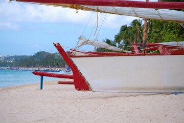 White beach of Boracay island. A sailing boat named Boracay is on the beach. Tourists walk along the beach and swim in the sea. A few days before the outbreak of the coronavirus.