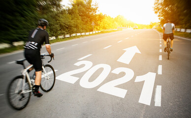 Two cyclist is moving straight to the 2021 year