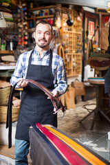 Happy young male worker demonstrating assortment in leather workshop