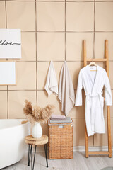 Modern interior of light bathroom with towels and bathrobe