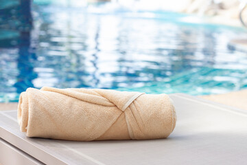 Folded towels are placed on a chair next to the swimming pool.