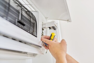 Installing an air conditioner in an apartment office, close-up of an engineer hand - obrazy, fototapety, plakaty
