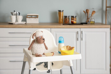 Baby highchair with food and toy in kitchen