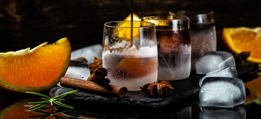 frozen herb liqueur in small glass. Shot glass of herb liqueur with cinnamon and oranges on a dark background