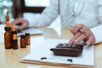 Fototapeta premium doctor with a stethoscope is use calculator to calculate medical expenses. For use in bulk orders of medicines And calculate income and expenses within the clinic receiving the treatment of patients